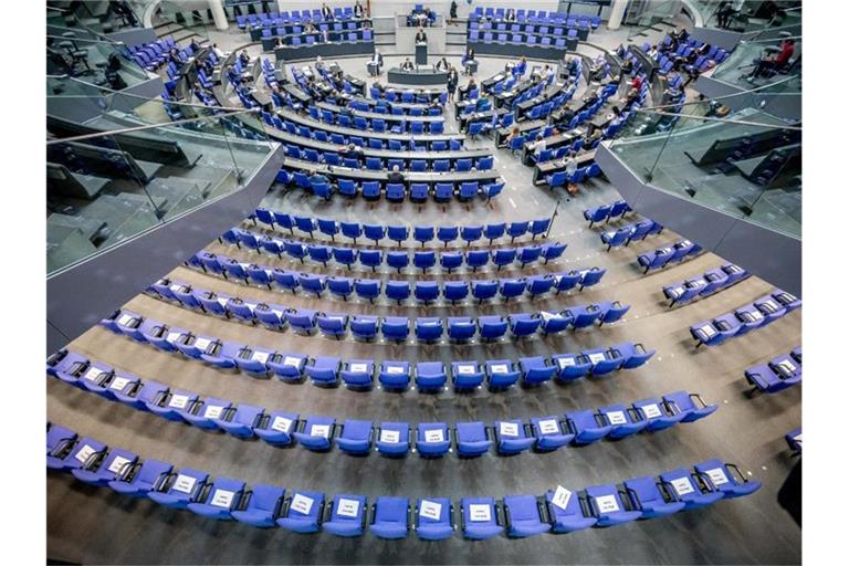 Stühle für die Abgeordneten, aufgenommen im Plenum in Deutschen Bundestag. Auf einigen der Stühle liegen Zettel mit der Aufschrift "Bitte frei lassen". Foto: Michael Kappeler/dpa