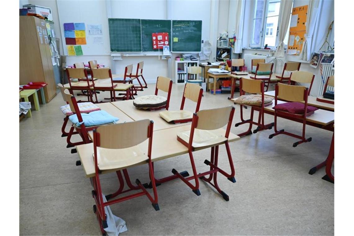 Stühle sind in einem leeren Klassenzimmer auf den Tischen abgestellt. Foto: Arne Dedert/dpa/Archivbild