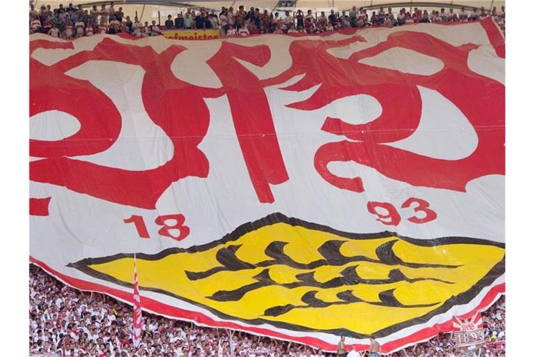 Stuttgarter Fans halten einen Banner mit dem Logo des VfB. Foto: Sebastian Kahnert/dpa/Archivbild