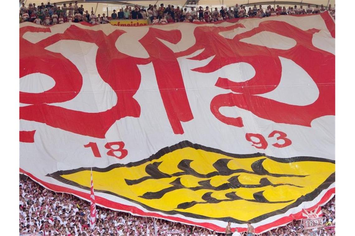 Stuttgarter Fans mit einem Banner mit dem Logo des VfB. Foto: Sebastian Kahnert/dpa/Archivbild