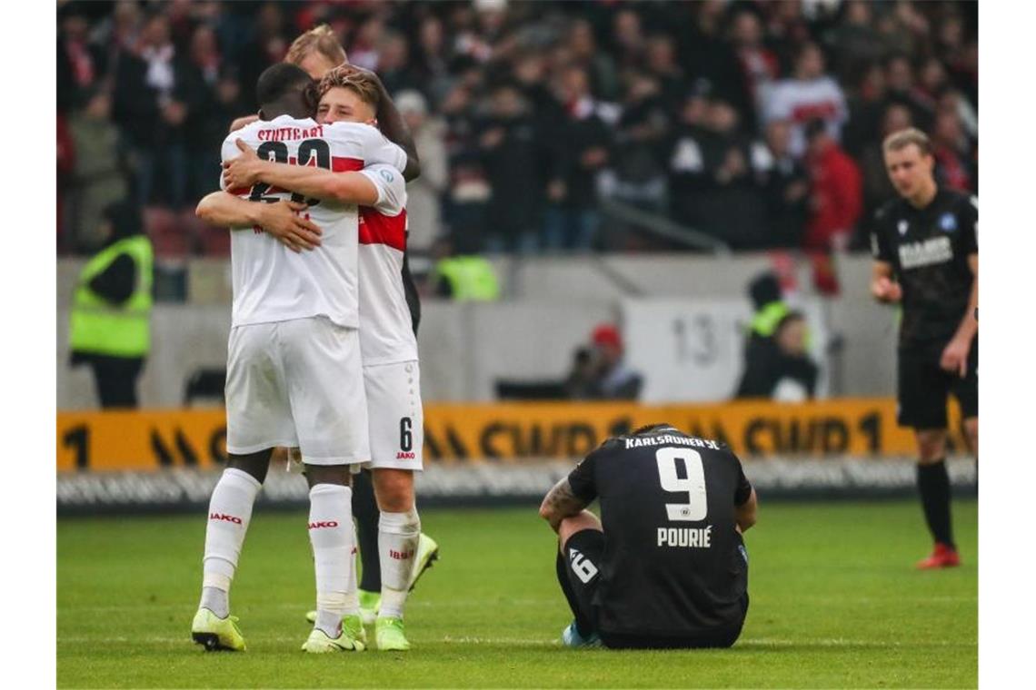 Stuttgarts Mangala und Ascacibar feiern nach Spielende, Karlsruhes Pourie ist enttäuscht. Foto: Christoph Schmidt/dpa