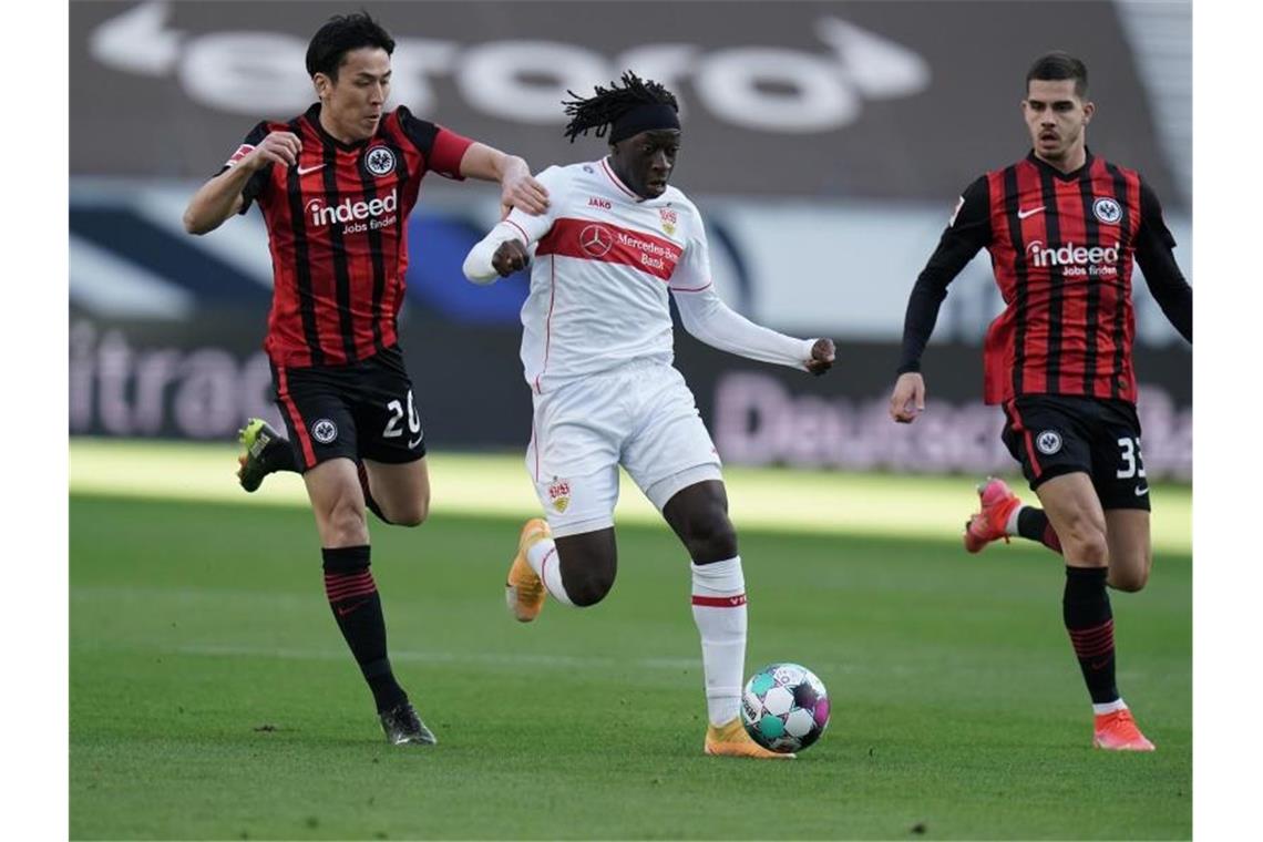 Stuttgarts Mittelfeldspieler Tanguy Coulibaly (M) versucht sich im Dribbling gegen zwei Frankfurter Gegenspieler durchzusetzen. Foto: Thomas Frey/dpa