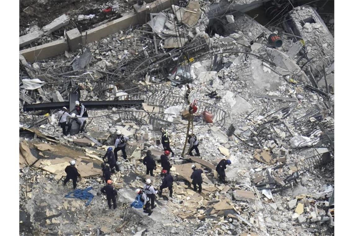 Such- und Rettungskräfte suchen nach Überlebenden in den Trümmern im dem teilweise eingestürzten zwölfstöckigen Gebäude. Foto: Gerald Herbert/AP/dpa