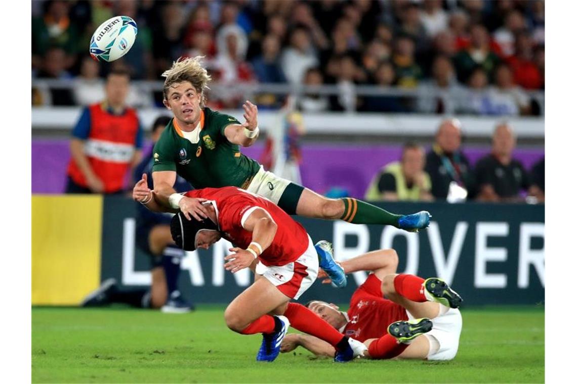 Rugby-WM: England wie im Rausch - Finale gegen Südafrika Südafrikas Faf de Klerk (oben) im Duell mit den Walisern Leigh Halfpenny (l) und Gareth Davies. Foto: Adam Davy/PA Wire/dpa