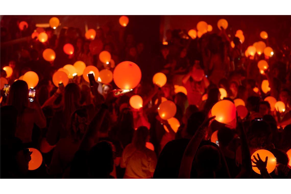 "Swifties" erleuchten in Bochum auf einer Party der Reihe "Taylor Party Europe" orangefarbene Luftballons mit den Lichtern ihrer Smartphones.