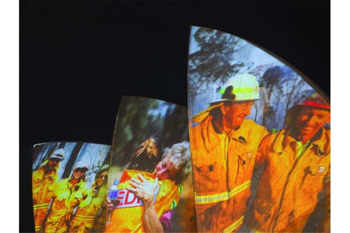 Symbolischer Dank an die Einsatzkräfte in Sydney: Auf die großen Segel des Opernhauses werden als Zeichen der Solidarität Bilder von Feuerwehrleuten projiziert. Foto: Paul Braven/AAP/dpa