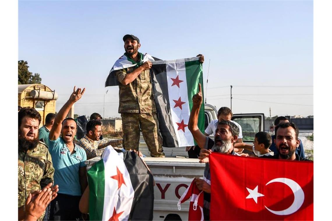 Syrische Oppositionskämpfer, die von der Türkei unterstützt werden, jubeln im türkischen Grenzort Akcakale. Foto: Uncredited/AP/dpa