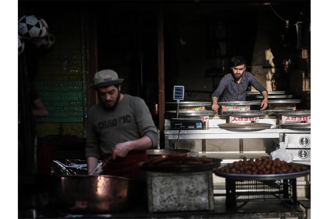 Ramadan: Geschlossene Moscheen und virtuelles Fastenbrechen Syrische Verkäufer bereiten auf einem Straßenmarkt traditionelle Süßigkeiten zu. Foto: Anas Alkharboutli/dpa