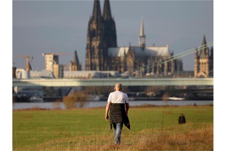 T-Shirt im Dezember: Ein Mann geht bei milden Temperaturen am Kölner Rheinufer in der Nachmittagssonne spazieren. Foto: Oliver Berg/dpa