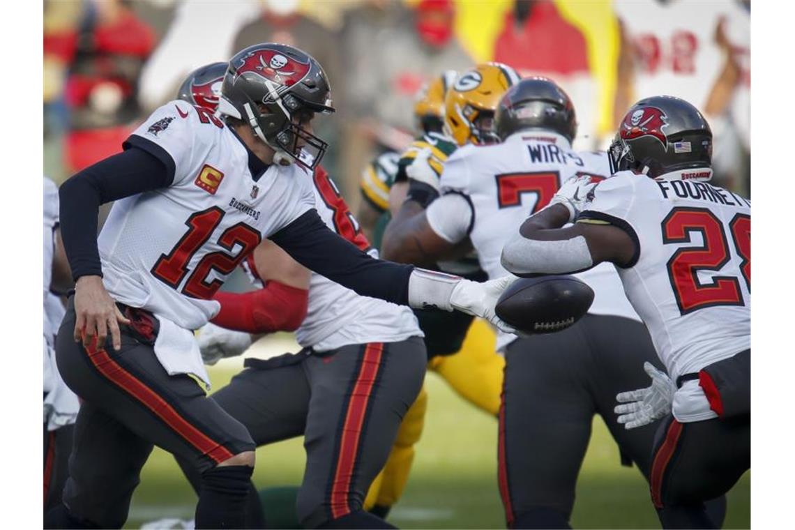 Super Bowl: NFL-Star Brady will Geschichte schreiben Tampa Bay Buccaneers-Quarterback Tom Brady (l) übergibt an Leonard Fournette (r) den Ball. Foto: Matt Ludtke/AP/dpa