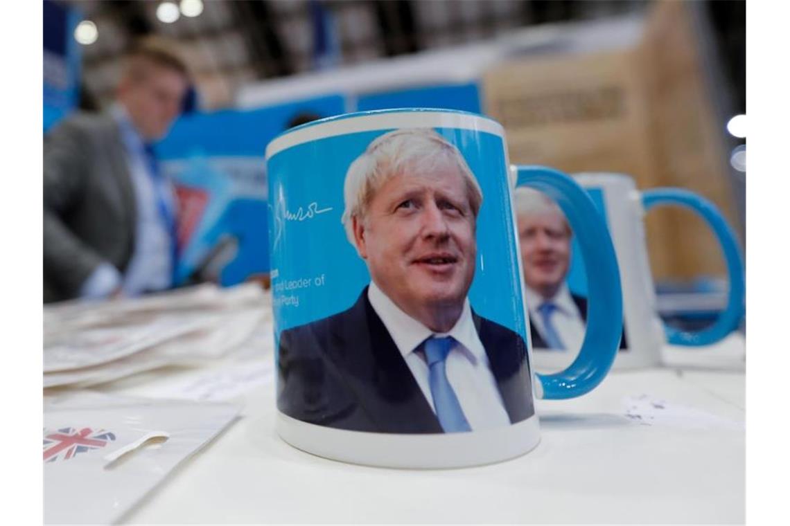 Berichte: Johnson will nach Parteitag Brexit-Pläne vorlegen Tassen mit dem Gesicht von Premierminister Boris Johnson auf dem Parteitag. Foto: Frank Augsteink/AP