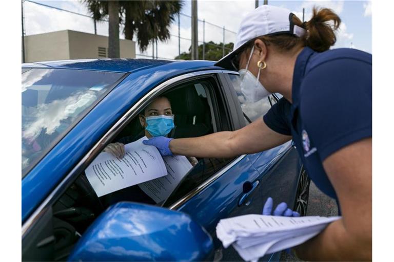 Tatiana Fernandez (r), Angestellte der Stadt Hialeah, verteilt Arbeitslosenformulare. Foto: Matias J. Ocner/TNS via ZUMA Wire/dpa