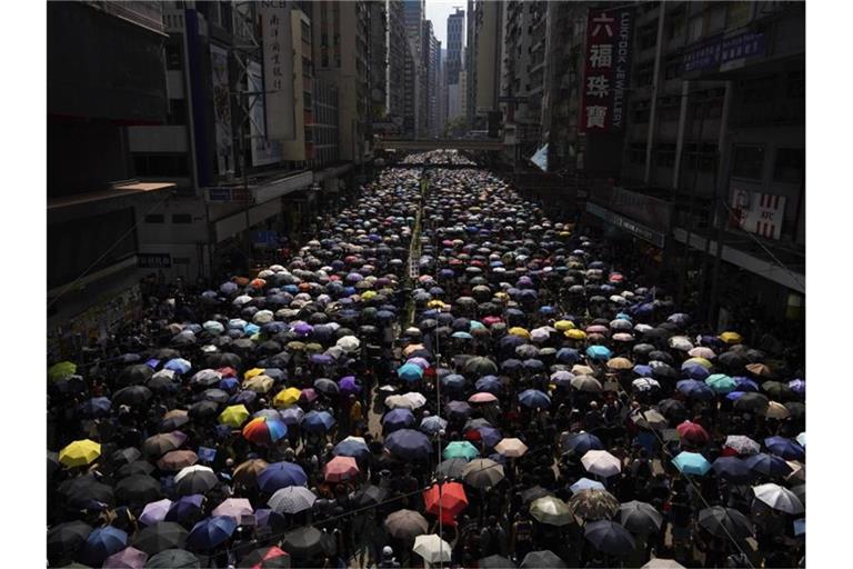 Tausende Hongkonger ziehen mit Regenschirmen über eine Straße. Foto: Vincent Yu/AP