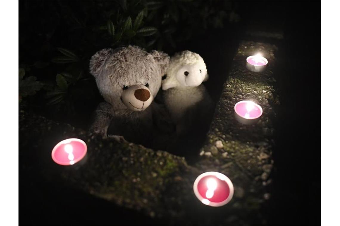 Teddybären und Kerzen liegen vor dem Haus, in dem die toten Kinder gefunden wurden. Foto: Roberto Pfeil/dpa