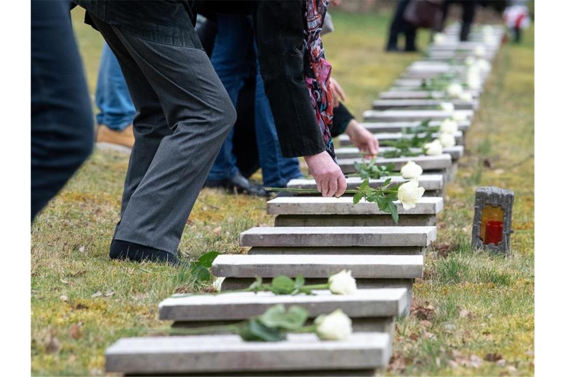 Gedenken in Pforzheim am 75. Jahrestag der Bombardierung Teilnehmende legen anlässlich des 75. Jahrestag der Bombardierung weiße Rosen auf Grabsteinen ab. Foto: Sebastian Gollnow/dpa
