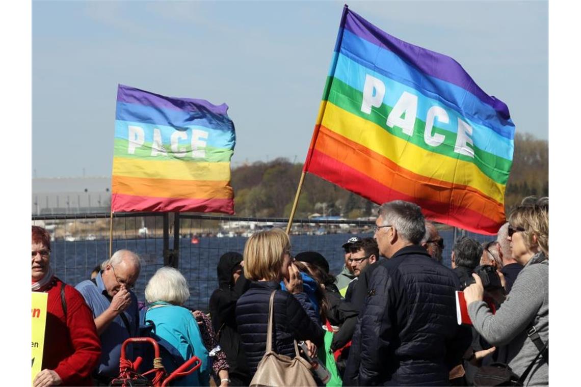 Teilnehmer an einem Ostermarch halten Fahnen der internationalen Friedensbewegung in die Höhe. Foto: Bernd Wüstneck/dpa-Zentralbild/ZB/Symbolbild