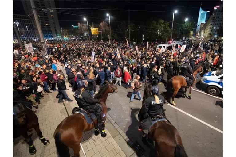 Teilnehmer der Demonstration stehen am Leipziger Hauptbahnhof vor der Reiterstaffel der Polizei. Foto: Sebastian Kahnert/dpa-Zentralbild/dpa