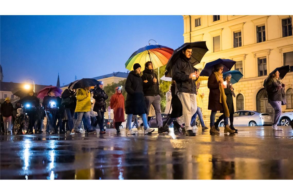 Teilnehmer des Schweigemarschs "Mach Dich auf für Menschlichkeit!" gehen mit Kerzen auf der Ludwigsstraße in München.