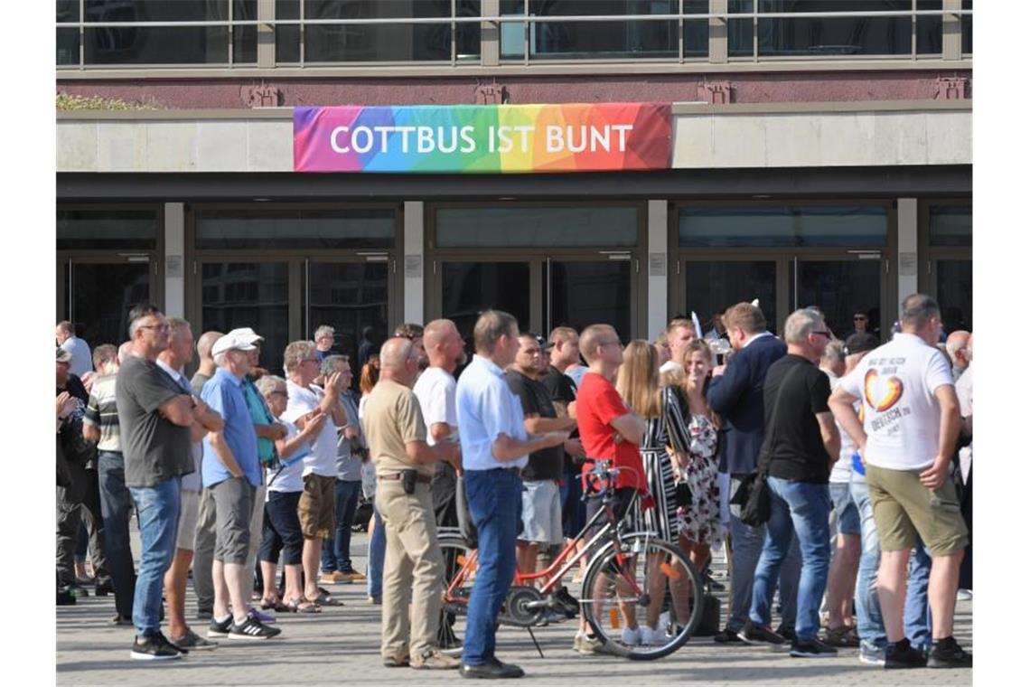 Höcke nutzt Frankfurter Bahnhofsattacke für Forderungen Teilnehmer des Wahlkampfauftakts der AfD-Jugendorganisation Junge Alternative stehen vor einem Transparent an der Stadthalle mit der Aufschrift „Cottbus ist bunt“. Foto: Patrick Pleul
