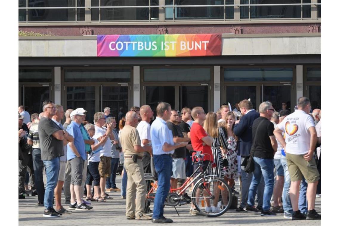 Teilnehmer des Wahlkampfauftakts der AfD-Jugendorganisation Junge Alternative stehen vor einem Transparent an der Stadthalle mit der Aufschrift „Cottbus ist bunt“. Foto: Patrick Pleul