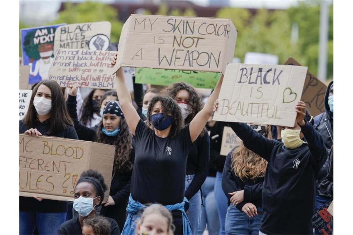 Teilnehmer einer Demo unter dem Motto „Nein zu Rassismus! Black lives matter“ halten Protestschilder. Foto: Uwe Anspach/dpa