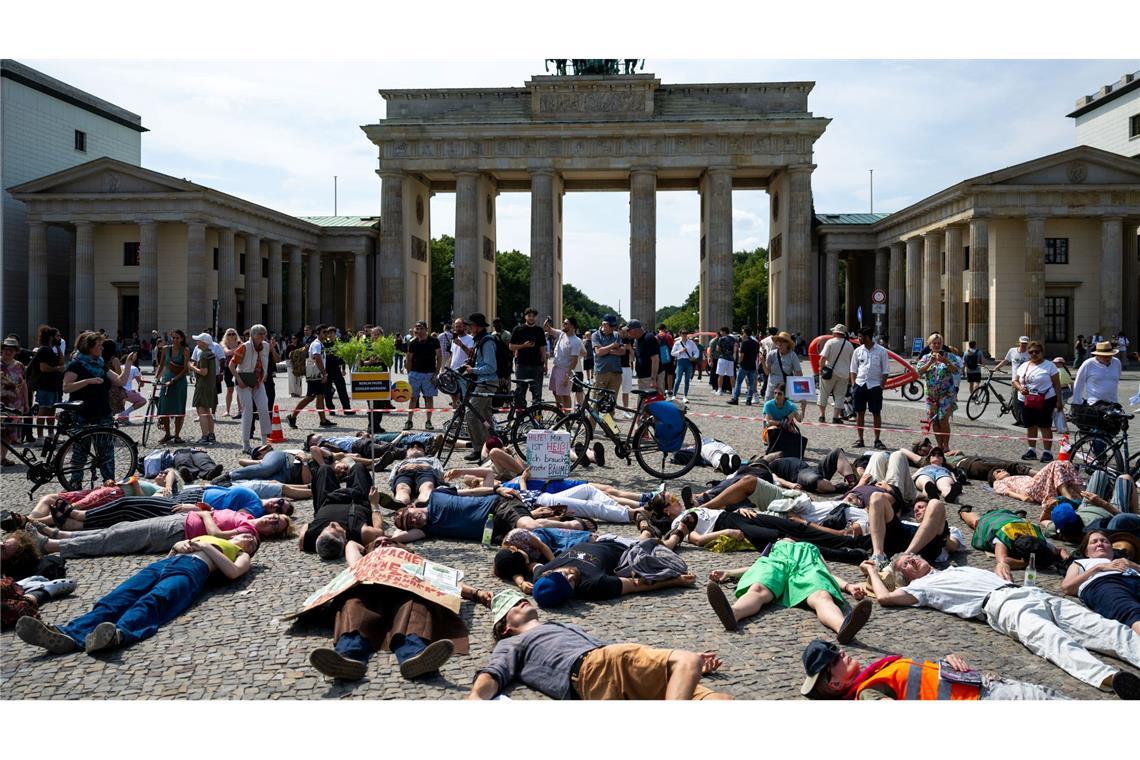 Teilnehmer einer Demonstration des Bündnisses "BaumEntscheid" liegen auf dem Boden auf dem Pariser Platz und simulieren einen Hitzetod.