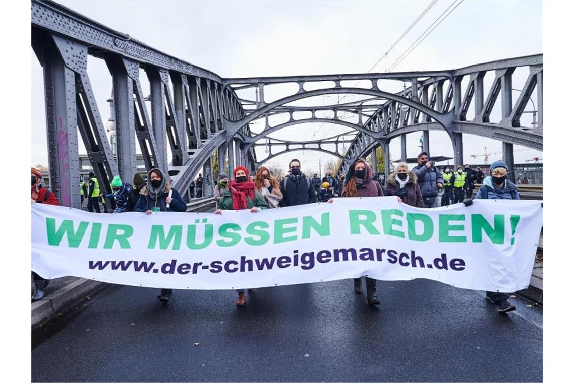 Teilnehmer einer Demonstration, die als „Schweigemarsch“ bezeichnet wird und sich gegen die Corona-Politik der Bundesregierung richtet, auf der Bornholmer Brücke. Foto: Annette Riedl/dpa