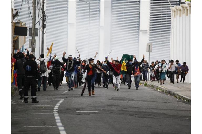Teilnehmer einer Demonstration fliehen in Quito vor einer Wolke Tränengas. Foto: Juan Diego Montenegro/dpa