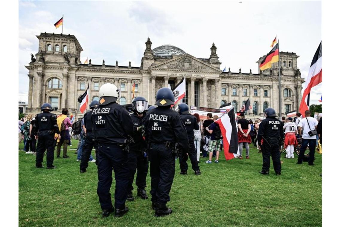 Teilnehmer einer Demonstration gegen die Corona-Maßnahmen stehen mit Reichsflaggen vor dem Reichstag. Foto: Fabian Sommer/dpa