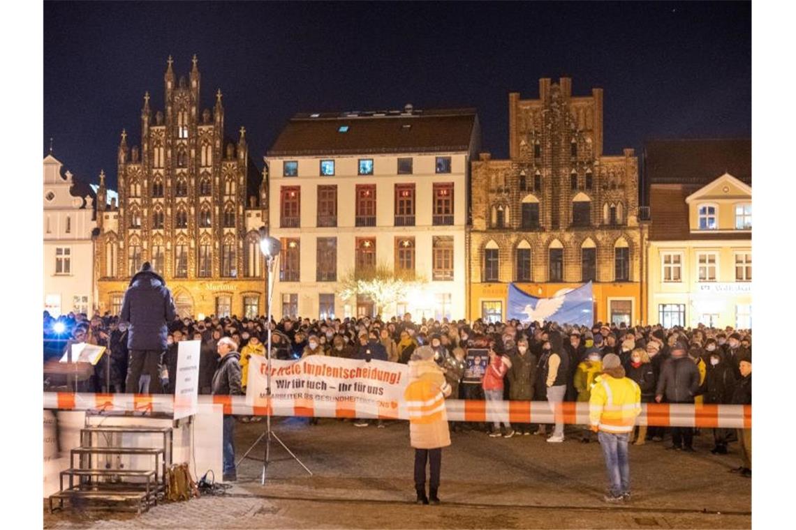 Bundesweit demonstrieren Tausende gegen Corona-Politik Teilnehmer einer Demonstration gegen die Corona-Maßnahmen stehen in Greifswald auf dem Markt. Foto: Stefan Sauer/dpa