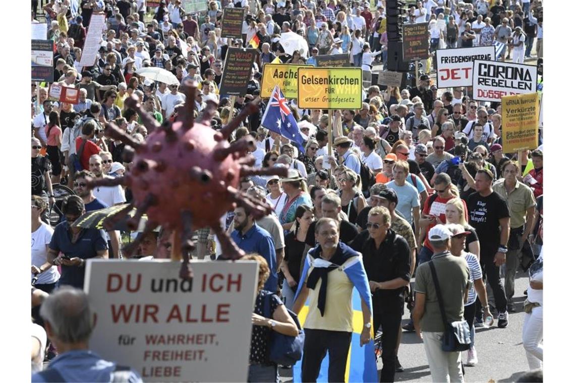 Teilnehmer einer Demonstration protestieren mit Schildern auf den Rheinwiesen gegen die Maßnahmen zur Bekämpfung des Coronavirus. Foto: Roberto Pfeil/dpa