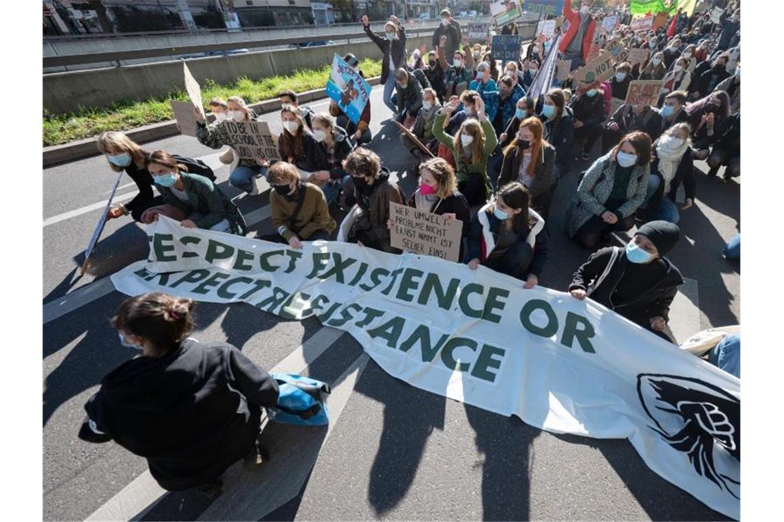 Teilnehmer einer Demonstration von „Fridays for Future“ sitzen mit einem Transparent auf der Straße. Foto: Marijan Murat/dpa