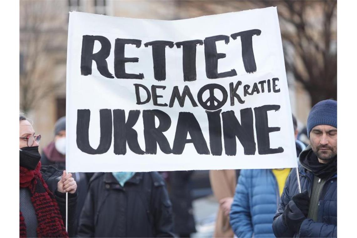 Tausende protestieren gegen Angriff Russlands auf Ukraine Teilnehmer einer Kundgebung für Frieden und gegen den russischen Einmarsch in die Ukraine am alten Markt in Magdeburg halten ein Plakat mit der Aufschrift „Rettet Demokratie Ukraine“. Foto: Matthias Bein/dpa-Zentralbild/dpa