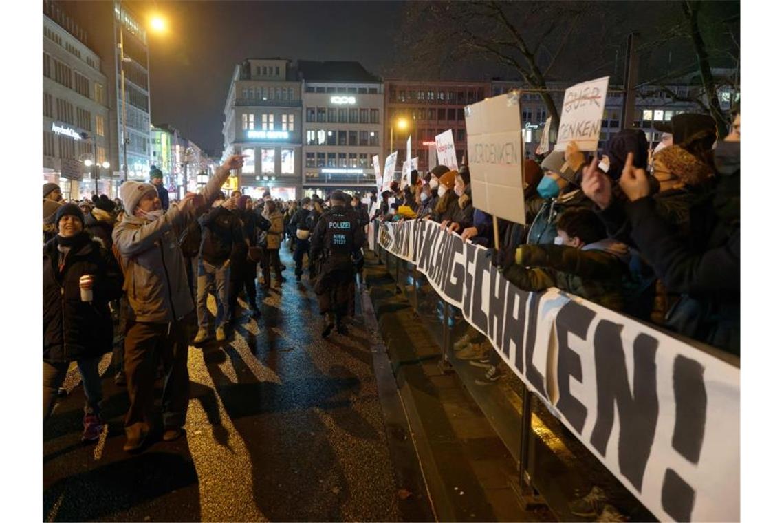 Teilnehmer einer Kundgebung gegen Corona-Maßnahmen und die einer Gegendemonstration stehen sich am Neumarkt in Köln gegenüber. Foto: Henning Kaiser/dpa