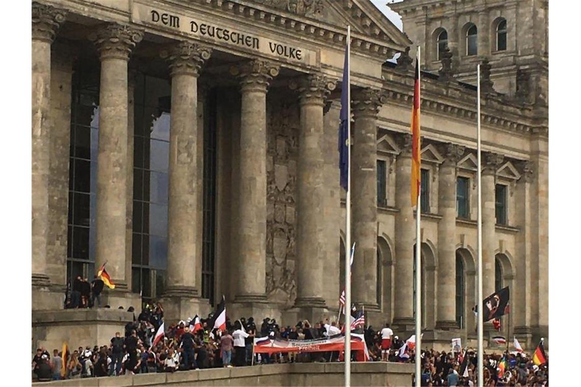 Teilnehmer einer Kundgebung gegen die Corona-Maßnahmen stehen vor dem Reichstag. Foto: Lukas Dubro/dpa