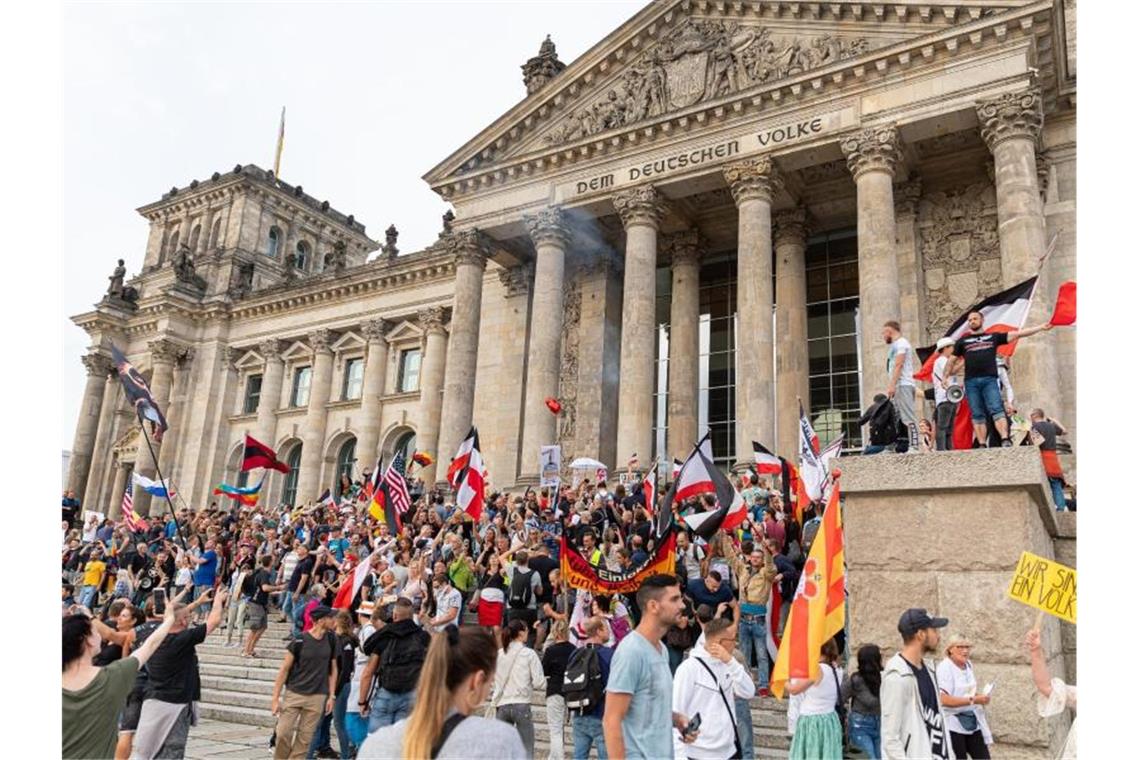 Krawall vor Reichstag - Scharfe Kritik aus der Politik Teilnehmer einer Kundgebung gegen die Corona-Maßnahmen stehen auf den Stufen zum Reichstagsgebäude, zahlreiche Reichsflaggen sind zu sehen. Foto: Achille Abboud/NurPhoto/dpa
