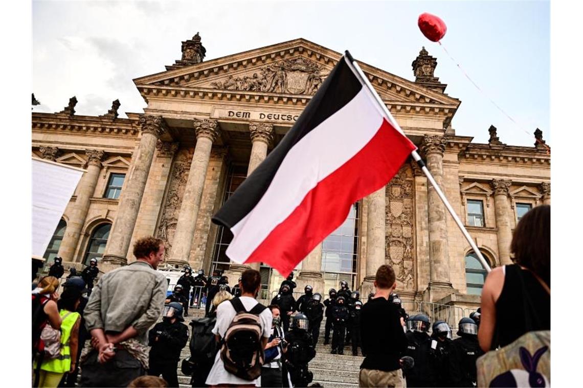 Teilnehmer einer Kundgebung gegen die Corona-Maßnahmen stehen Ende August vor dem Reichstag, ein Teilnehmer hält eine Reichsflagge. Foto: Fabian Sommer/dpa