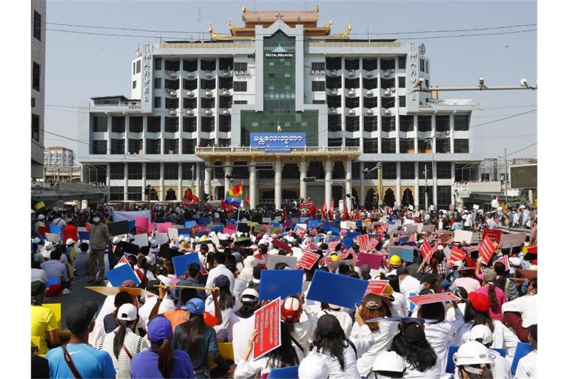 Teilnehmer eines Protestmarschs gegen den Militärputsch versammeln sich mit Plakaten vor dem Bahnhofsgebäude in Mandalay. Foto: Uncredited/AP/dpa