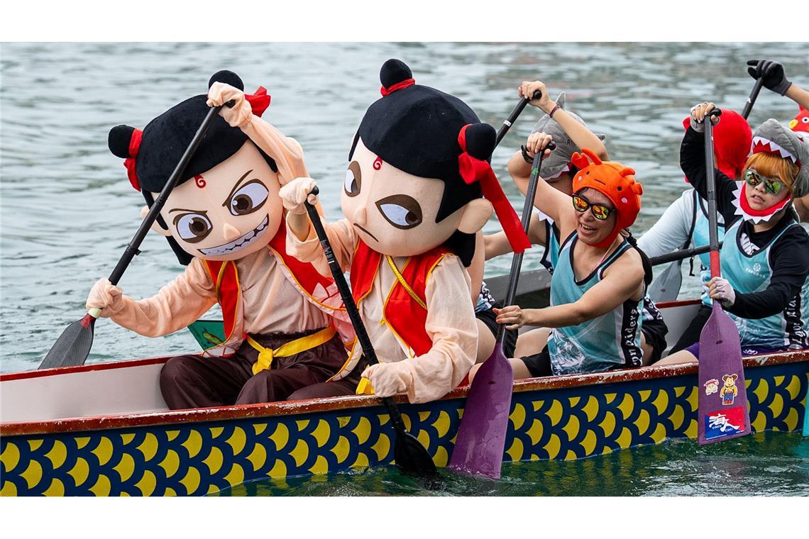Teilnehmer in bunten Kostümen rudern beim Drachenbootfest in Hongkong.