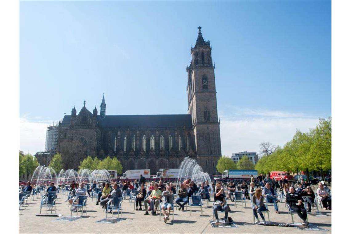 Leere Stühle: Gastronomen weisen auf prekäre Lage hin Teilnehmer lassen sich in Magdeburg nach dem Ende der Aktion vor dem Dom auf den Stühlen nieder. Foto: Klaus-Dietmar Gabbert/dpa-Zentralbild/dpa