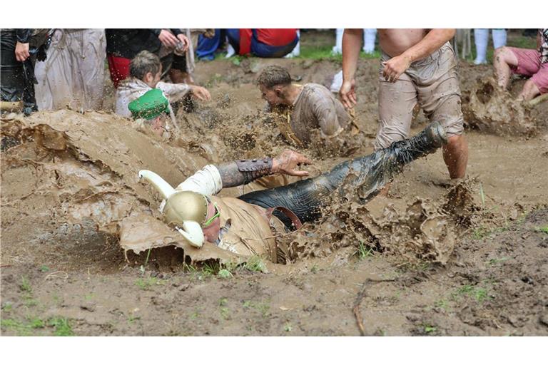 Teilnehmer springen auf dem Dreckschweinfest 2025 auf dem Festivalgelände auf der Wildbahn in ein Schlammloch.