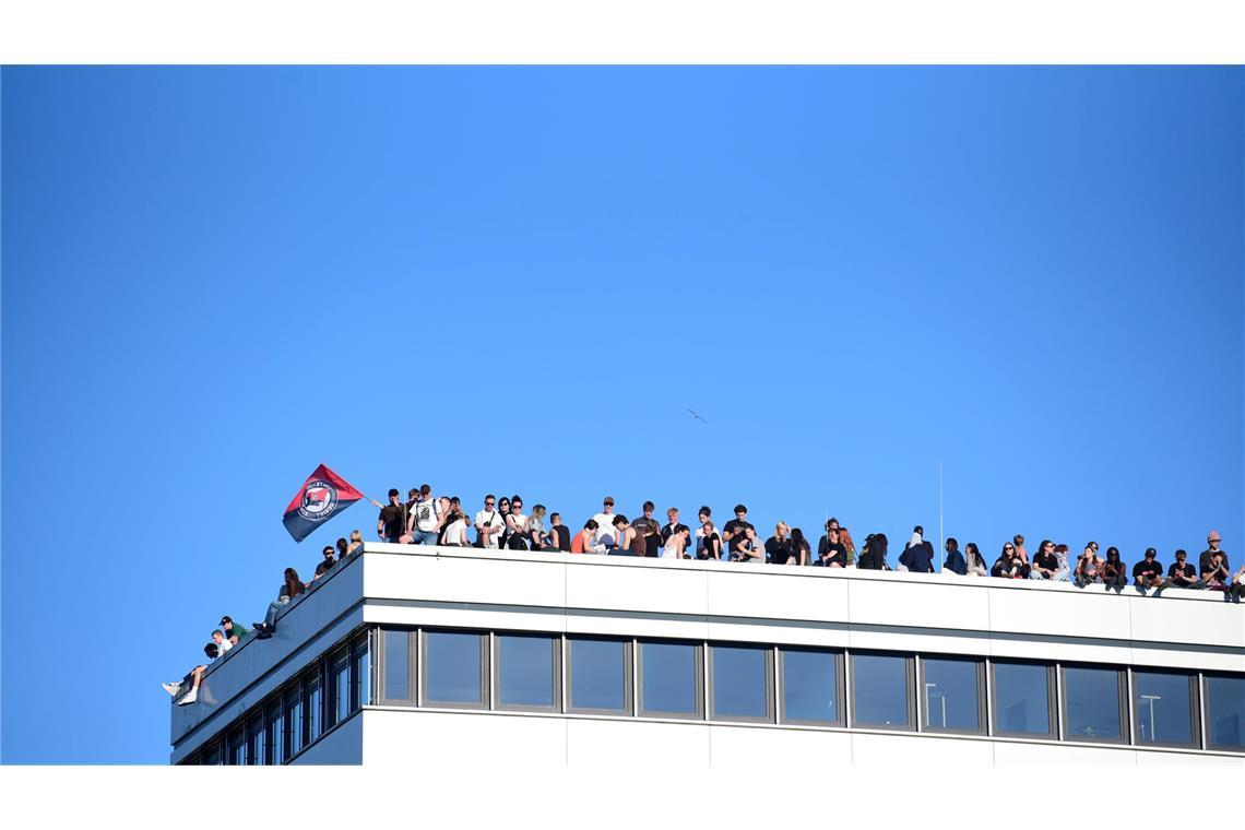 Teilnehmer stehen bei einer Demonstration mit dem Motto "Krieg und Krise haben System. Als Klasse vereint: Sozialismus erkämpfen!" auf dem Dach eines Hauses in Hamburg.