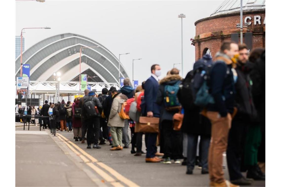 Obama in Glasgow: „Welt muss sich jetzt bewegen“ Teilnehmer und Teilnehmerinnen stehen vor dem Gelände der UN-Klimakonferenz COP26 in Glasgow am Einlass Schlange. Foto: Christoph Soeder/dpa