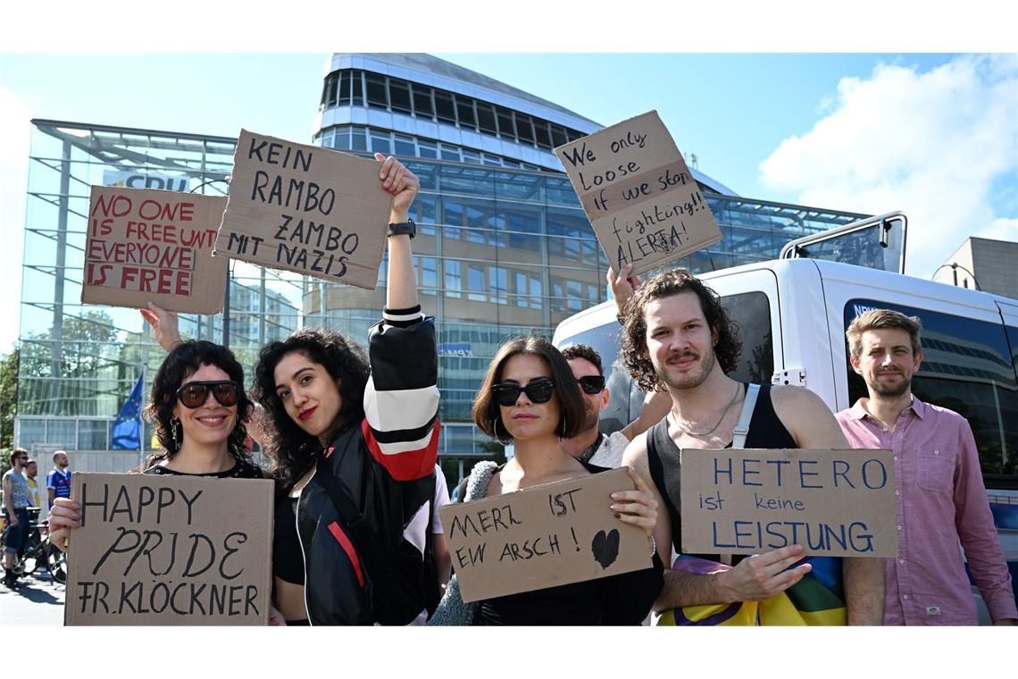 Teilnehmerinnen und Teilnehmer greifen auf ihren Plakaten auch die Kontroverse um die Regenbogenflagge am Bundestag auf.