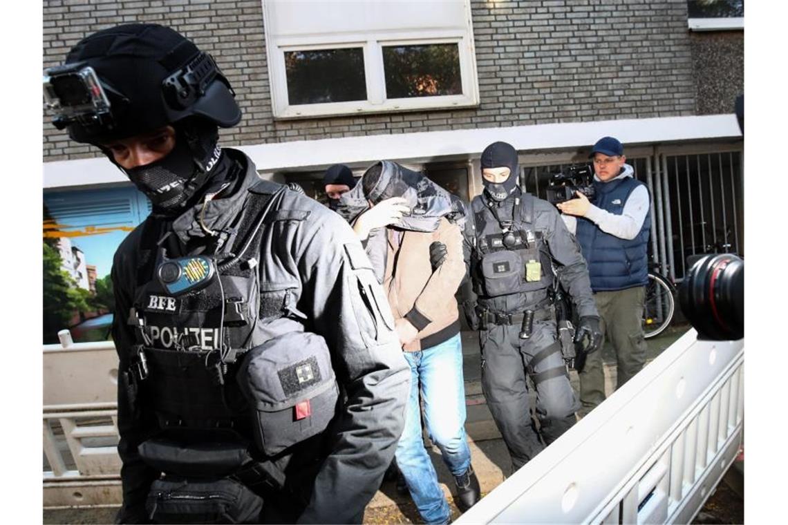Terror-Razzia in Hamburg: Ein Mann wird von Polizisten aus einem Haus geführt. Foto: Christian Charisius