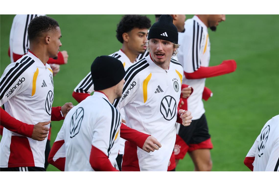 Thiaw (l.) und Woltemade (mit Mütze in der Mitte) laufen beim DFB-Training.