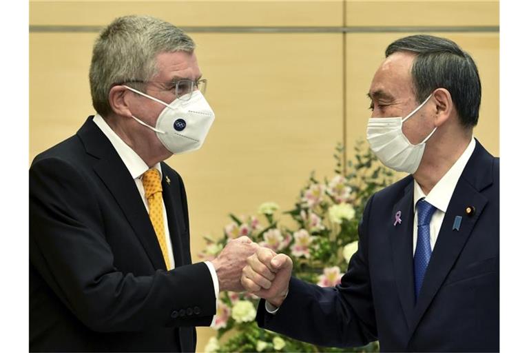 Thomas Bach (l), Präsident des Internationalen Olympischen Komitees, und Yoshihide Suga, Premierminister von Japan, begrüßen sich. Foto: Kazuhiro Nogi/AFP Pool/AP/dpa