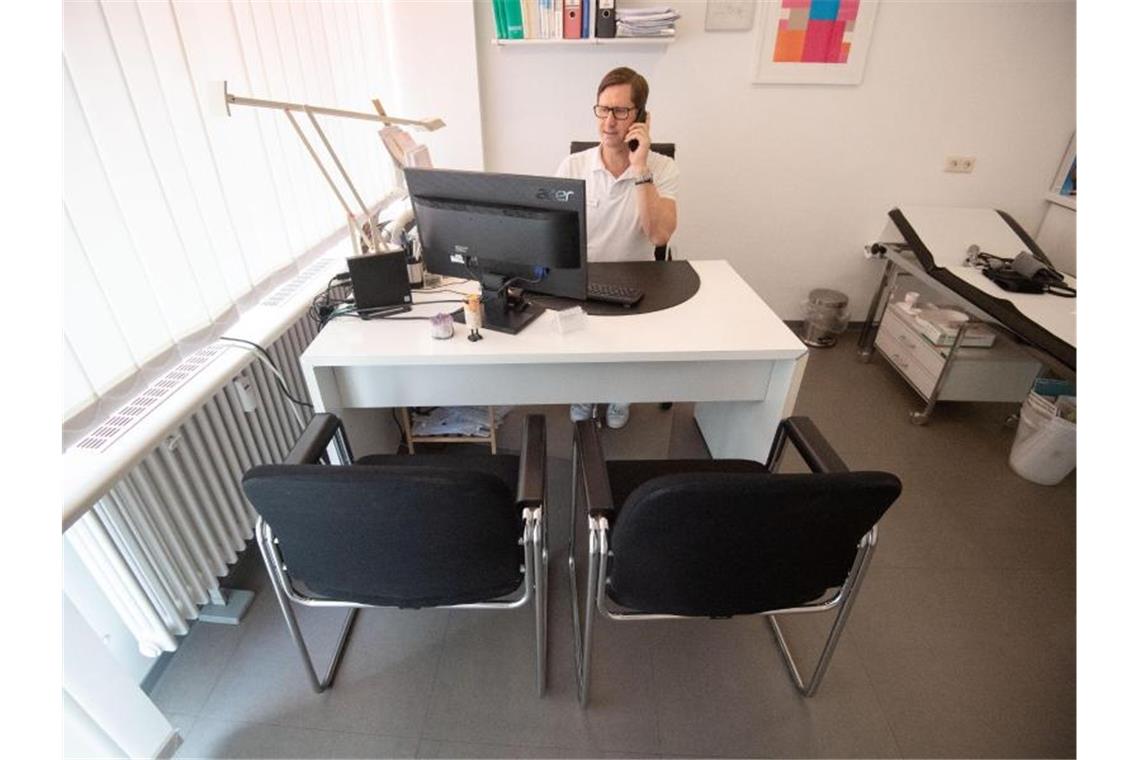 Viel Interesse an Telemedizin, Ärzte bleiben aber skeptisch Thomas Heyer sitzt in seiner Hausarztpraxis mit einem Telefonhörer am Ohr in einem Behandlungszimmer. Foto: Marijan Murat/dpa
