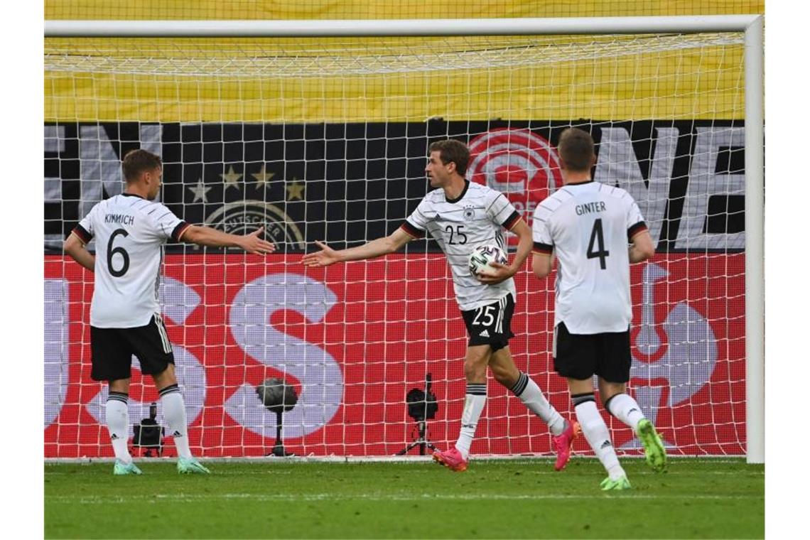Thomas Müller (M.) holt nach seinem Tor zum 3:0 den Ball aus dem Netz. Foto: Federico Gambarini/dpa