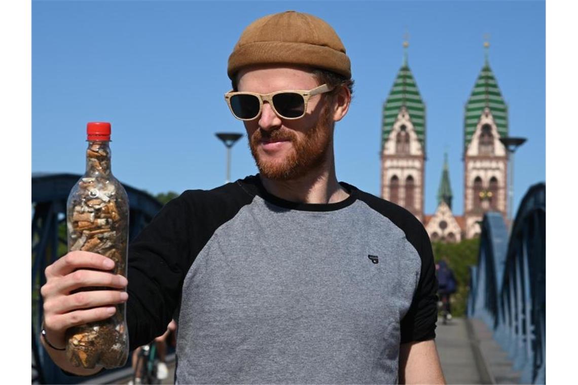 Till Neumann von der Band Zweierpasch hält eine Plastikflasche mit Zigarettenstummeln in der Hand. Foto: Patrick Seeger